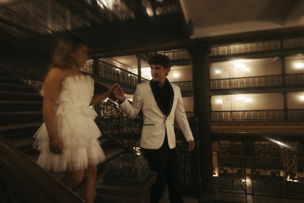 A wedding couple walking down a staircase together 