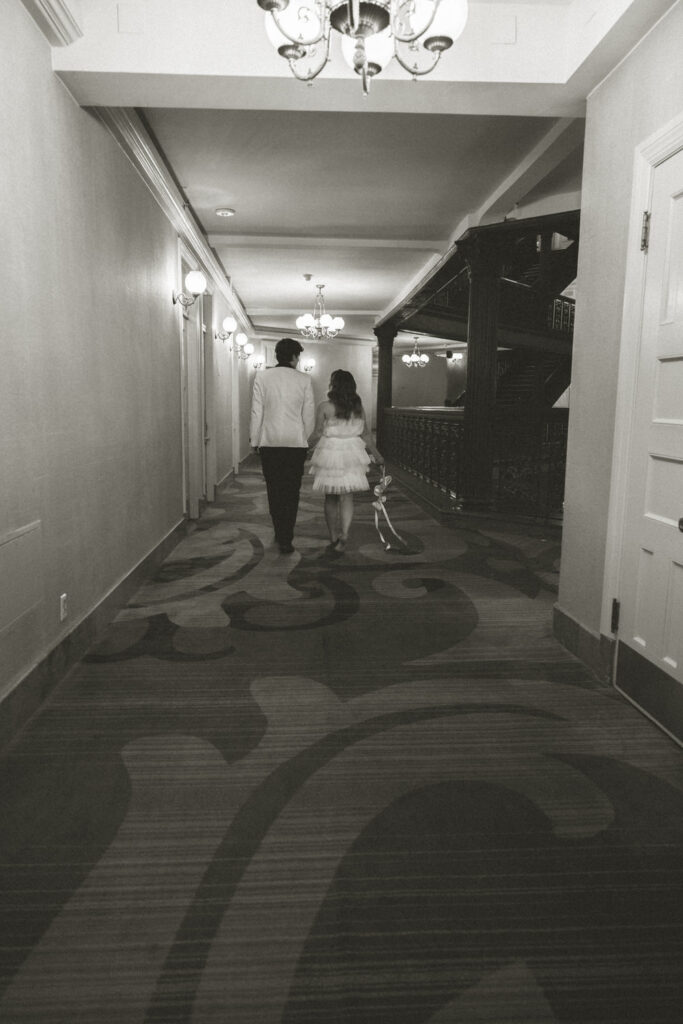 A wedding couple walking down a hotel hallway. 