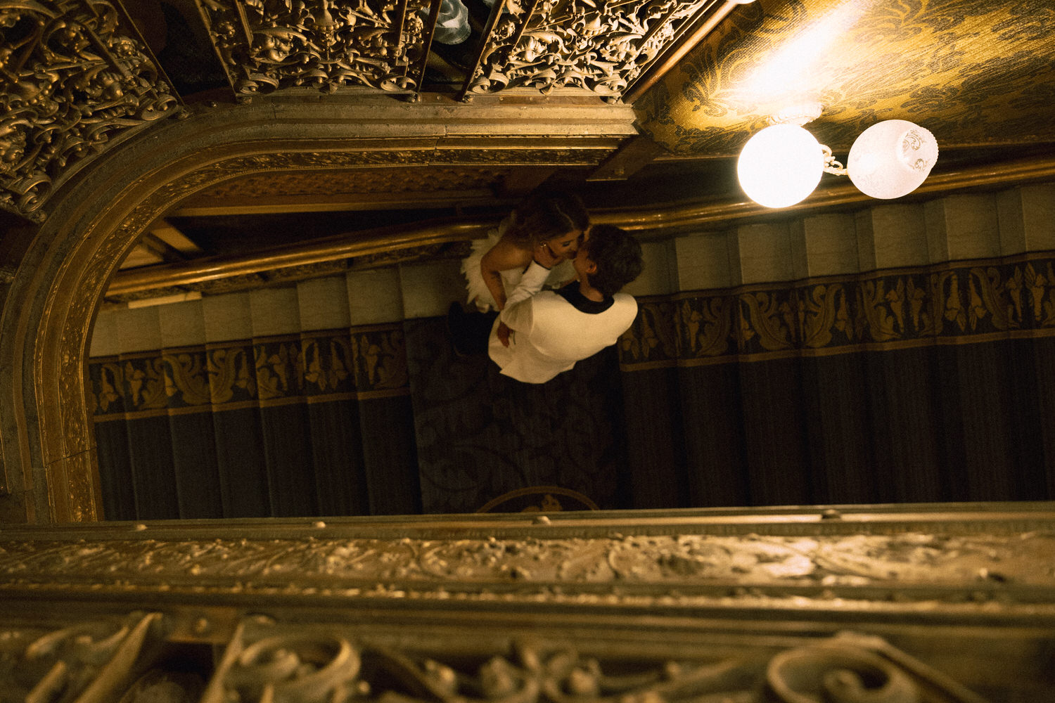 Cinematic wedding photography of a wedding couple kissing on a staircase taken from above.