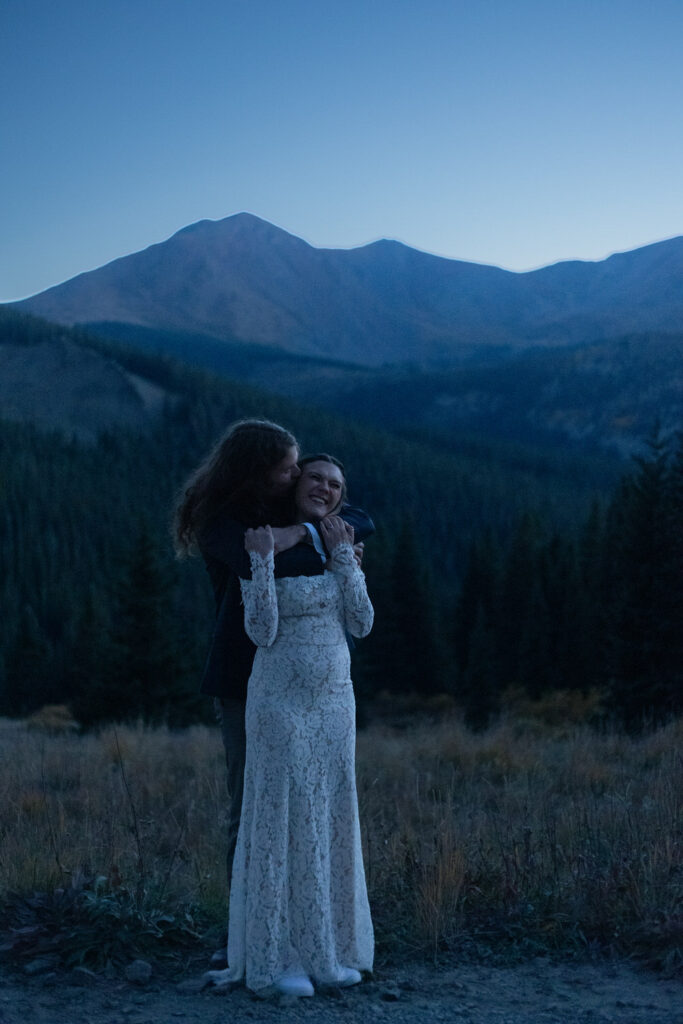 A person hugging their partner from behind and kissing their cheek 