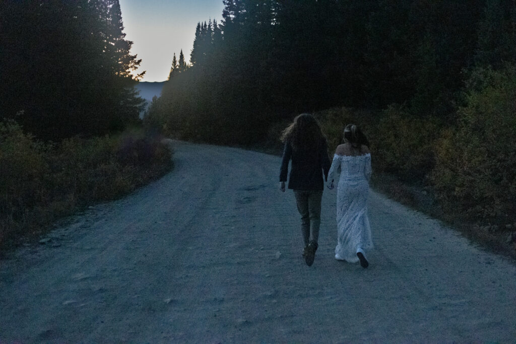 A couple holding hands and walking along a mountain road. 