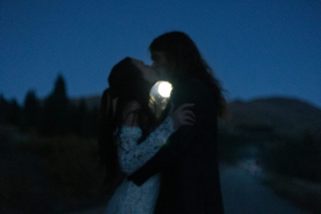 A couple kissing with the moon shining between them .