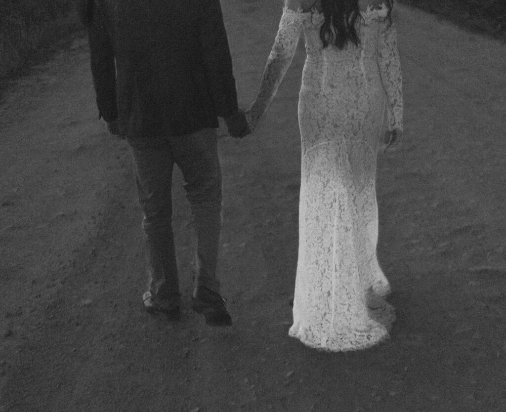 A couple holding hands and walking along a road. 