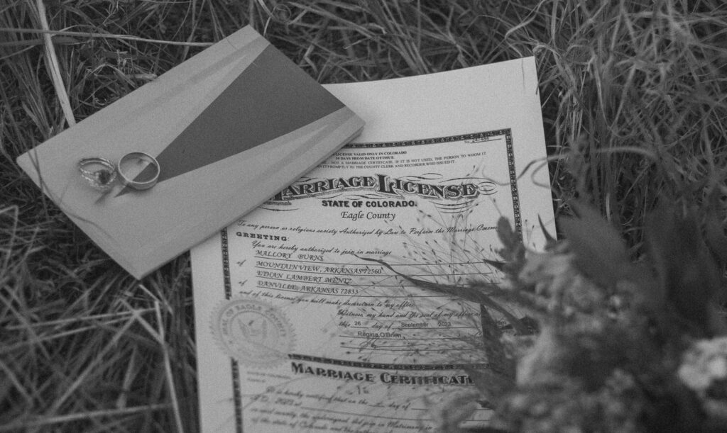 Wedding rings and a marriage certificate laying in the grass. 