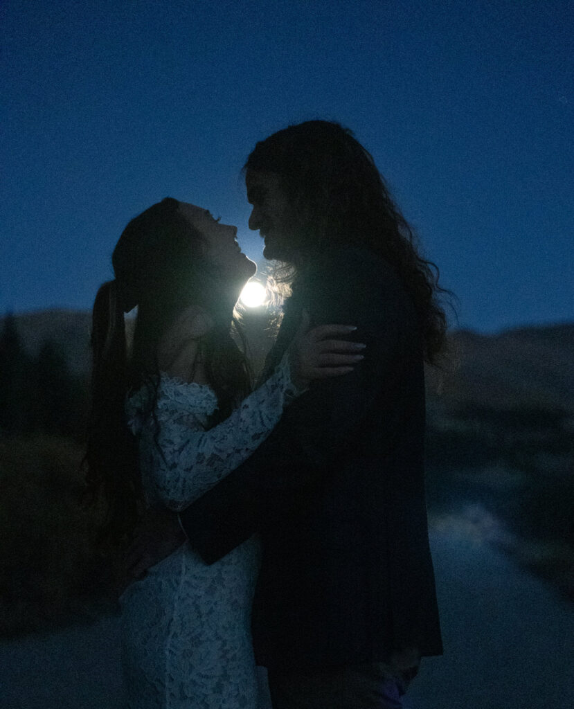 a couple laughing and about to kiss under the moonlight. 