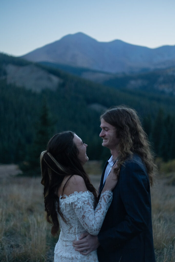 A wedding couple standing close together and smiling. 