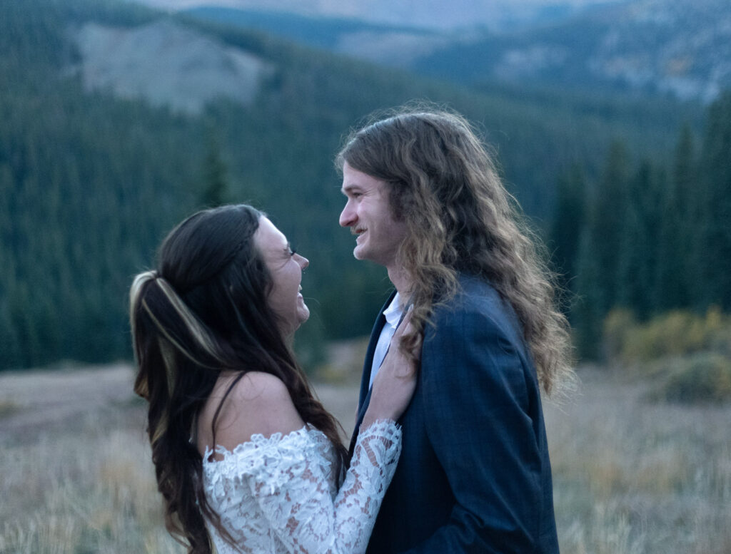 A wedding couple standing close together and laughing 