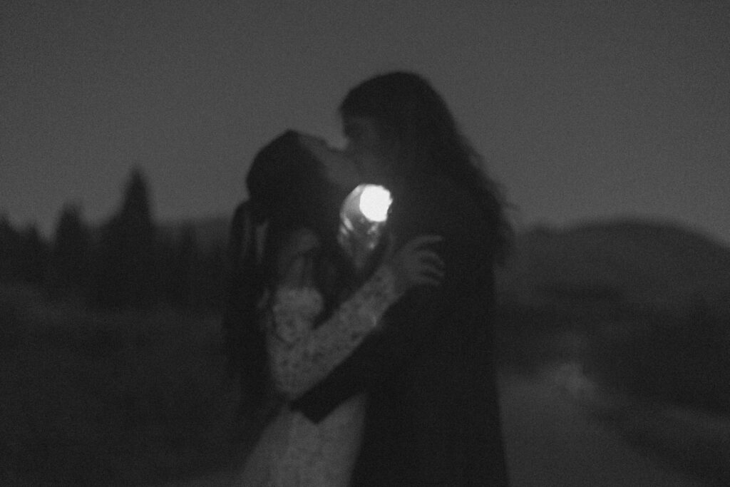 A couple kissing with the moon shining in the distance 