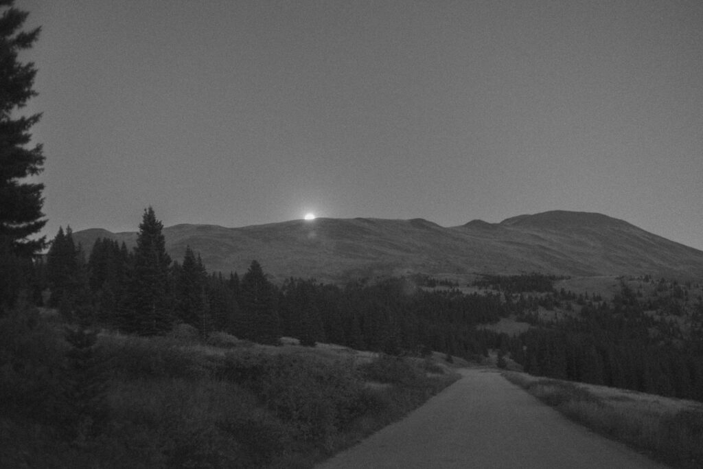 Black and white photo of the moon over the mountains 