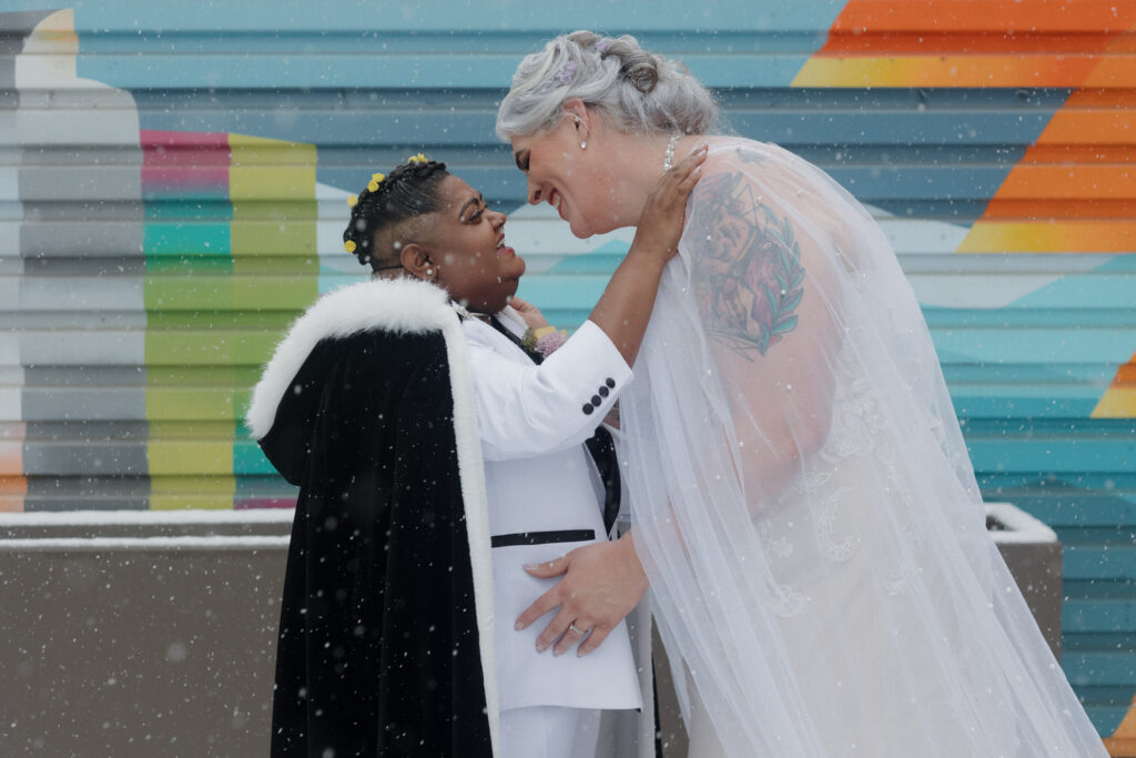 A newlywed couple about to kiss in the snow
