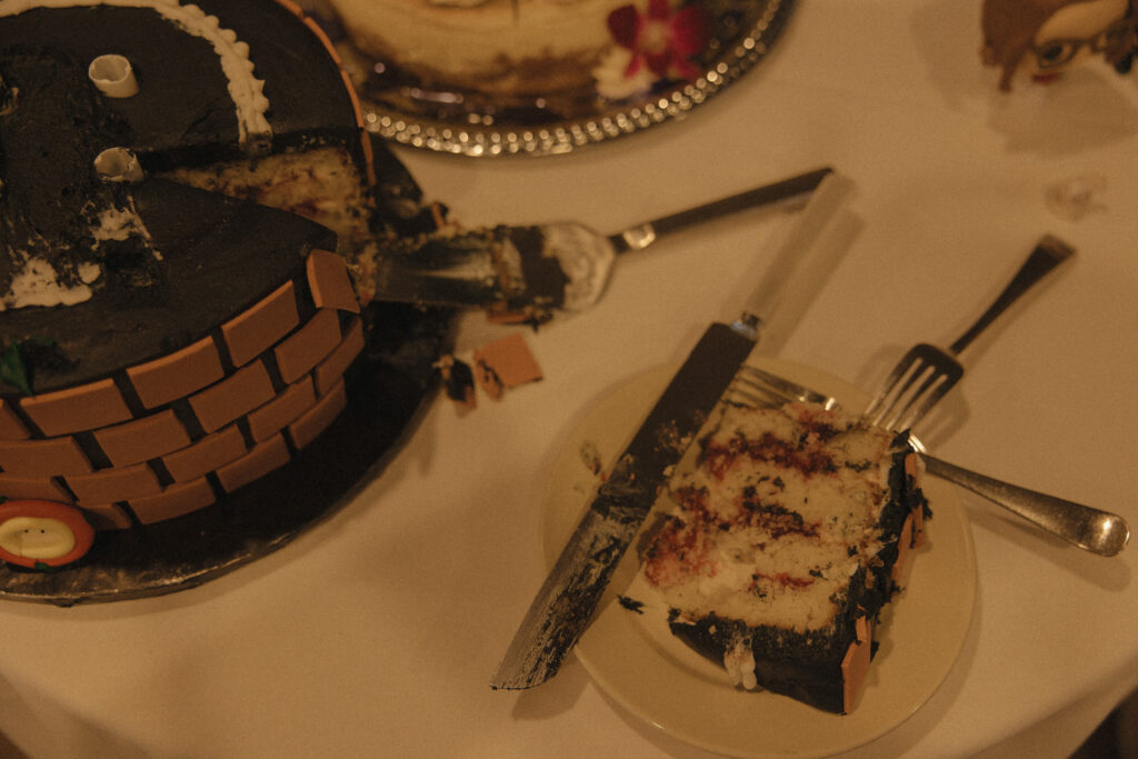 A piece of a wedding cake sitting on a plate next to the rest of the cake