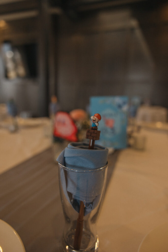 A small Mario figure on a block sticking out of a glass. 