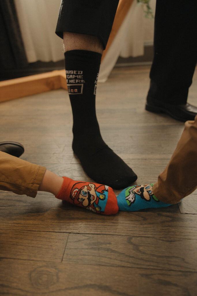 Three people's feet with Mario themed socks on 