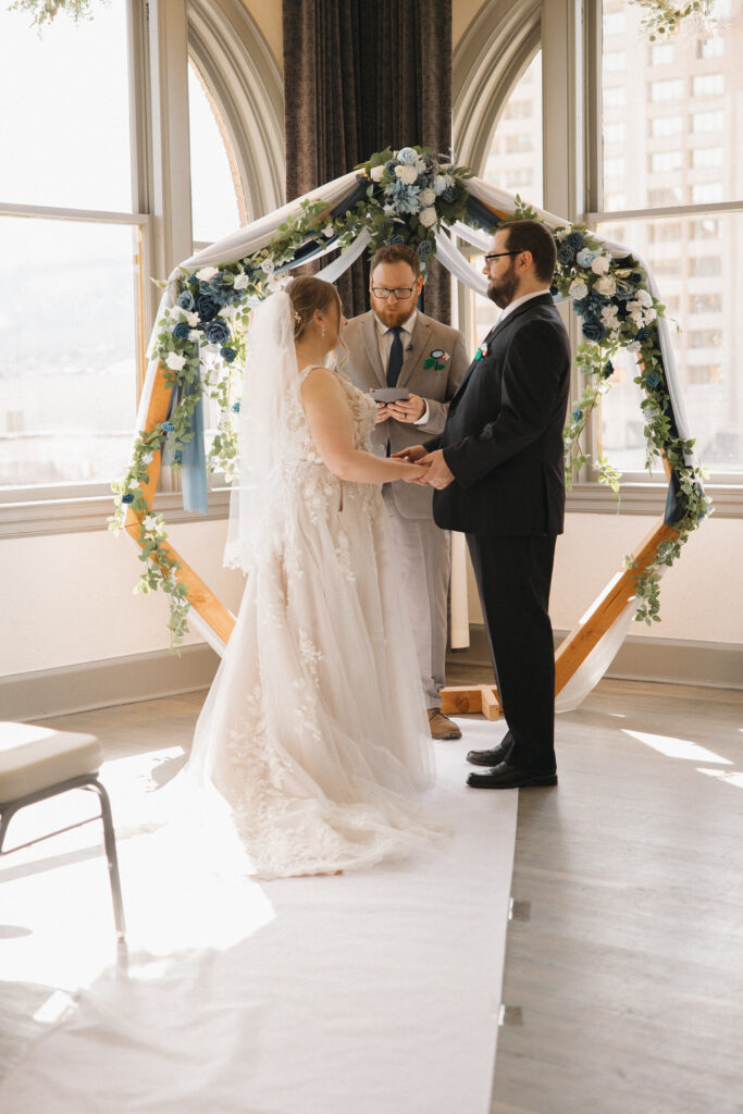 A wedding couple standing up and saying their vows together. 