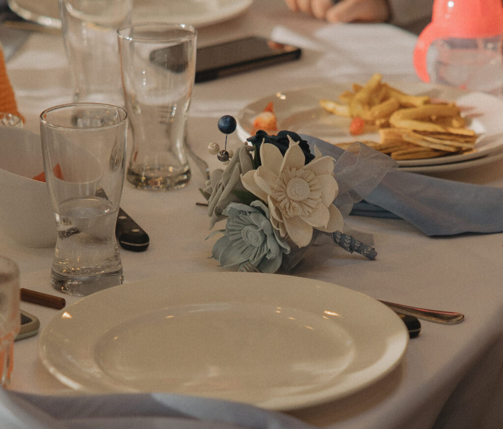 A reception table with white places and blue and white flowers 