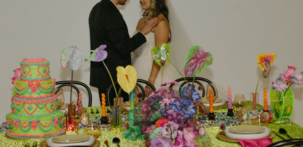 A person putting their hand over their partner's heart while standing behind a decorated table. 