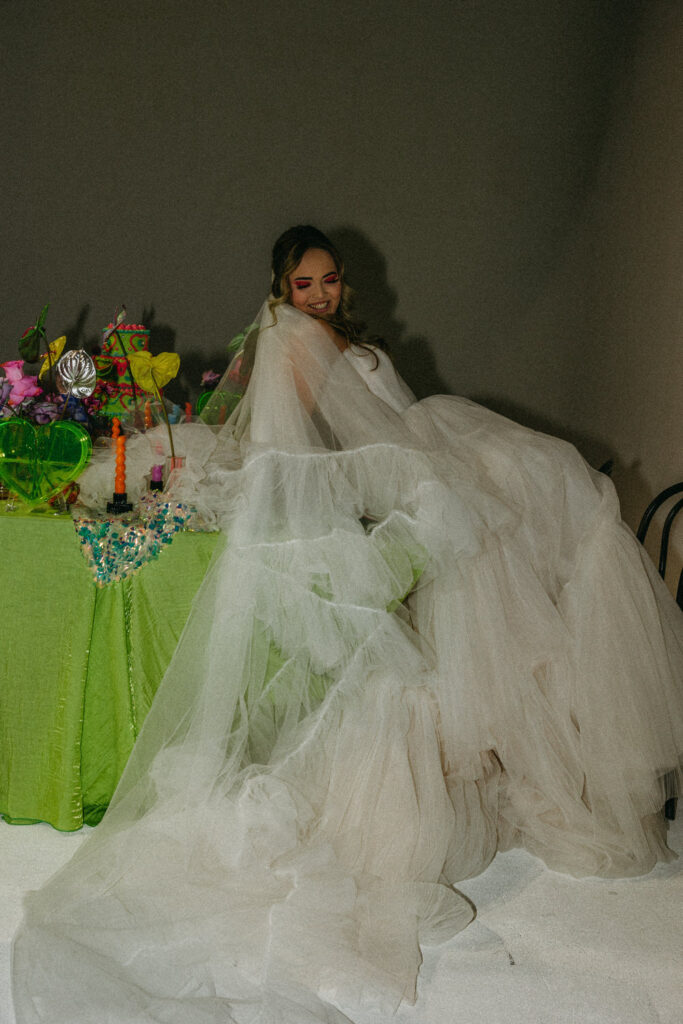 A person in a wedding dress sitting on the edge of a wedding reception table. 