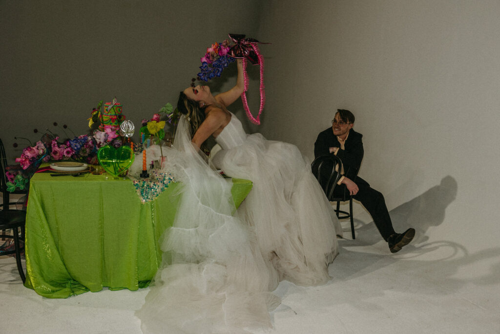 A person sitting on a table holding up a bouquet of flowers while their partner sits next to them. 