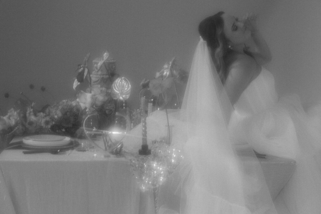 A person in a wedding dress leaning back on a wedding reception table. 