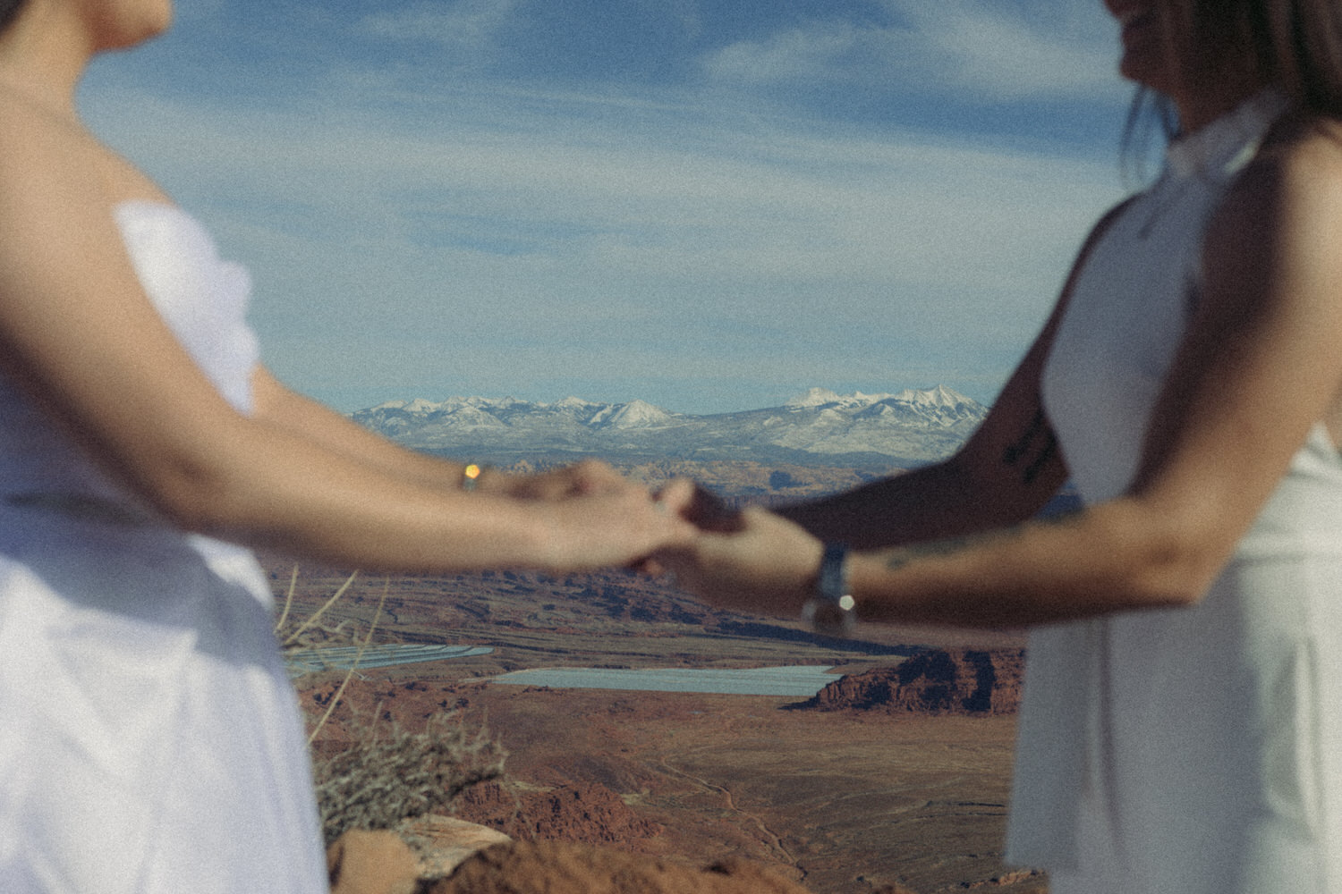 A couple holding holds with a canyon in the distance as they elope in Utah.