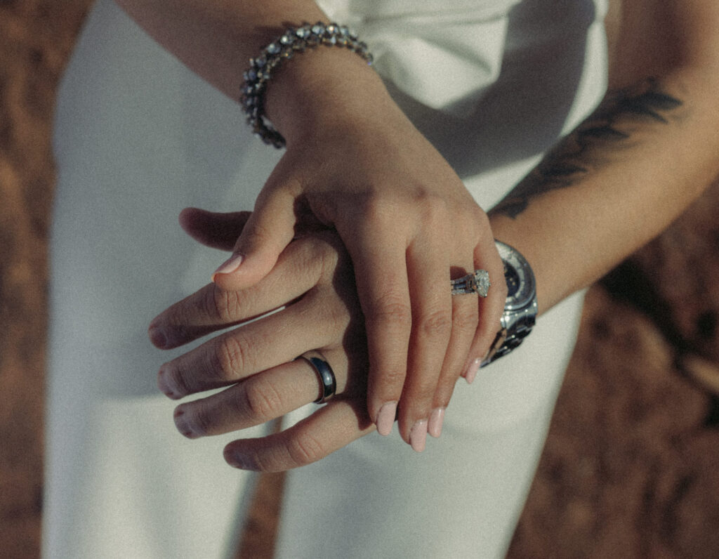 Two hands laid on top of each other showing off wedding rings. 