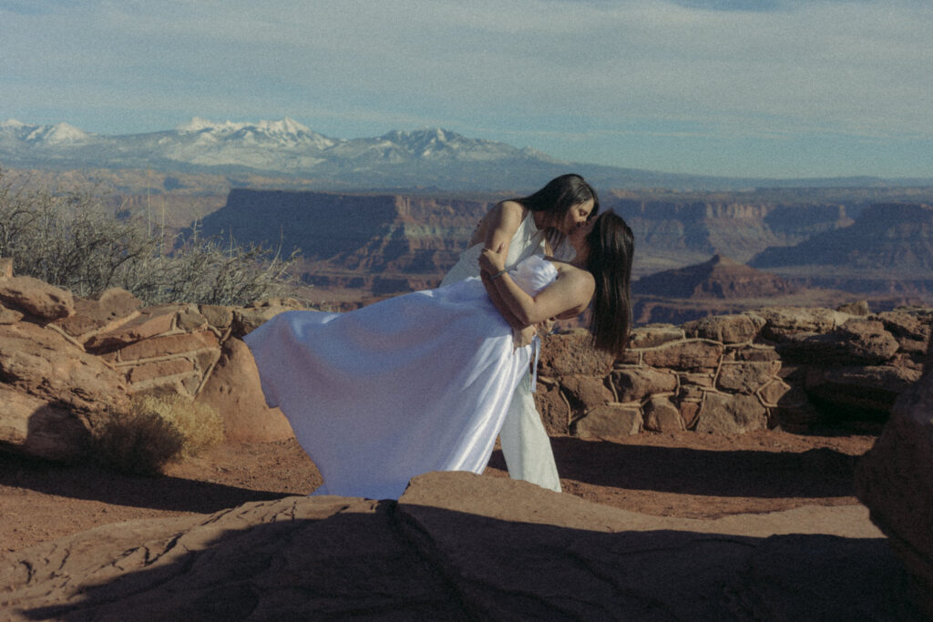 A person dipping their partner and kissing them on their wedding day. 