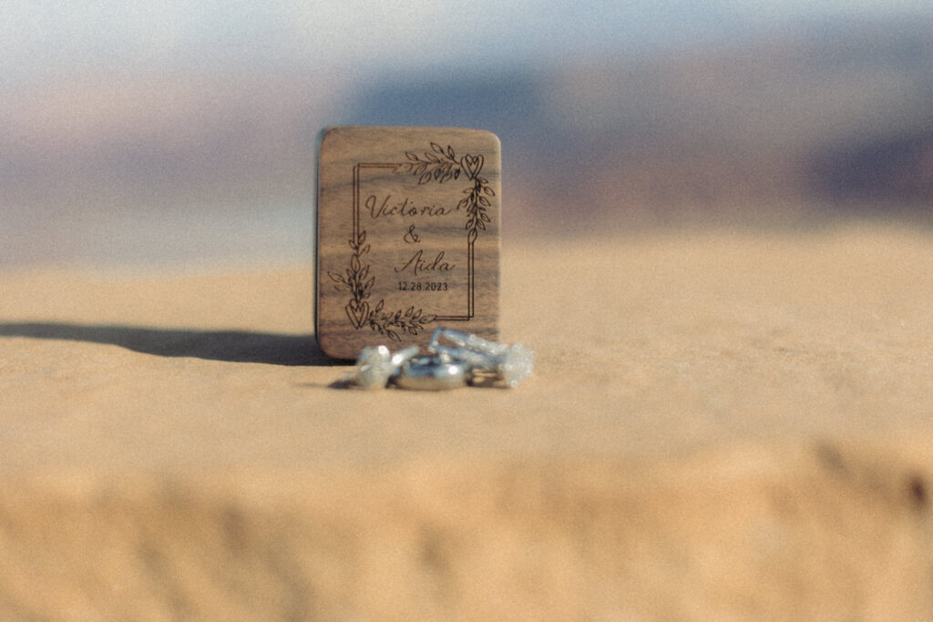 Wedding rings laid in front of a small wooden box with names engraved in it