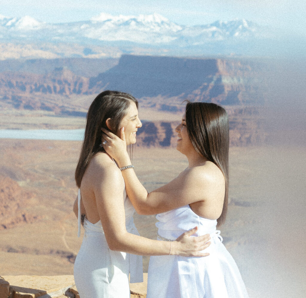 A person holding their partner's face and smiling on their wedding day. 