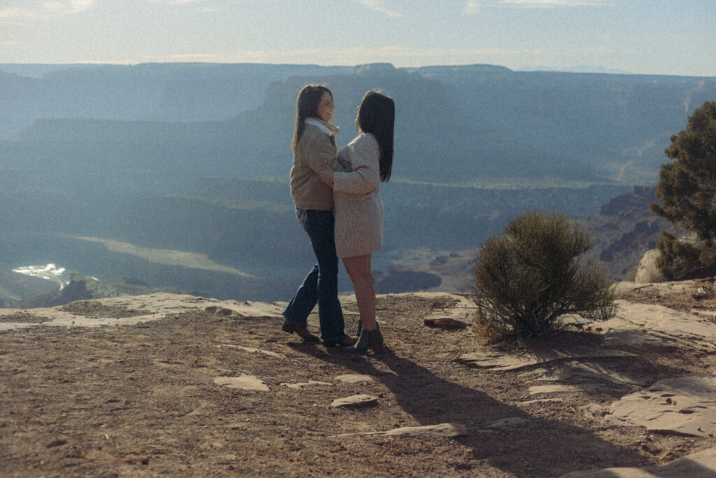 A couple holding each other and smiling at the top of a canyon 