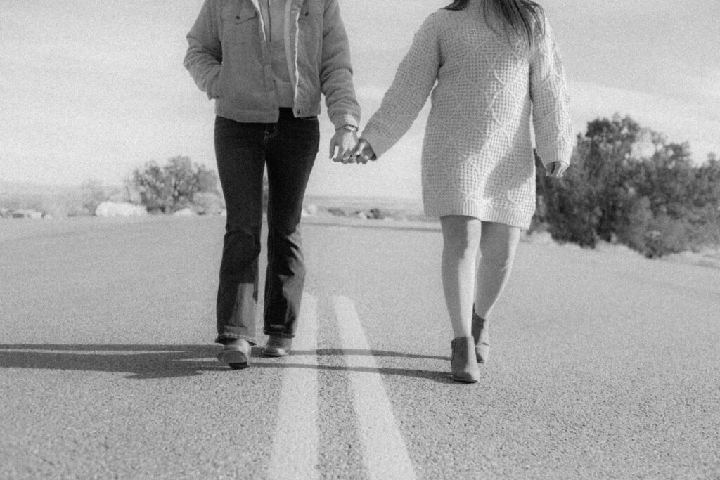 A couple holding hands and walking along a road 