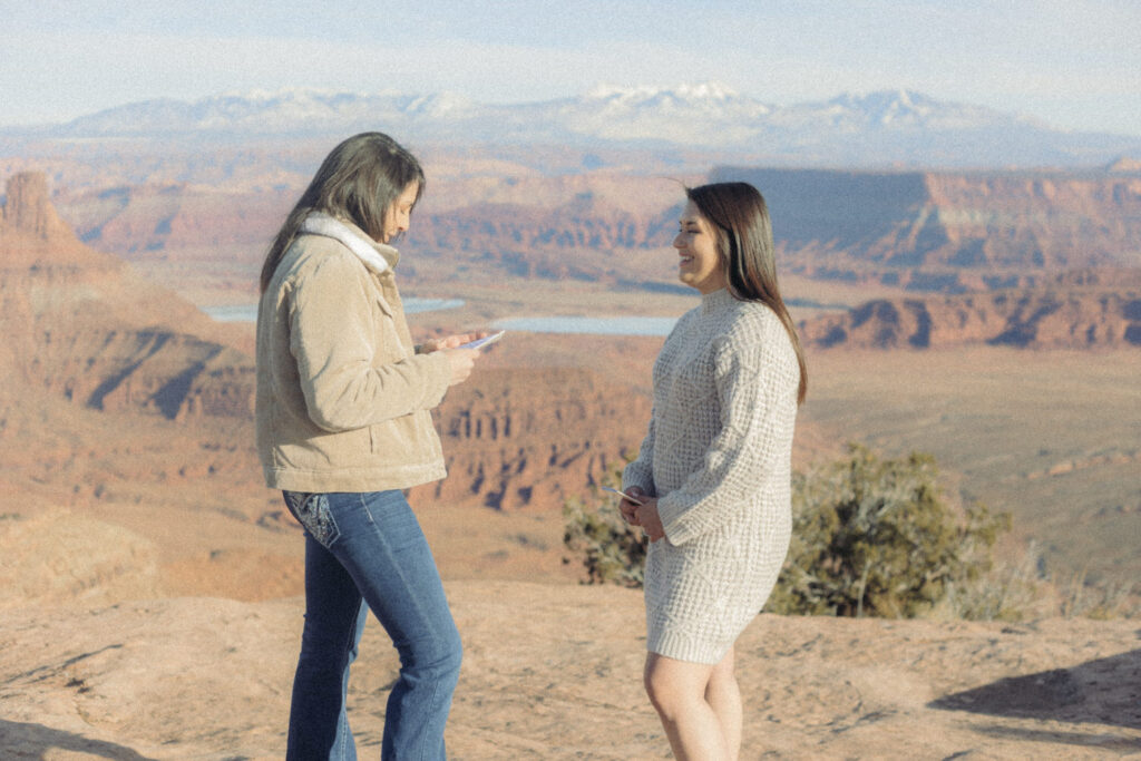 A person reading a note to their partner at the top of a canyon 